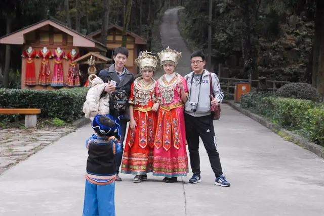 Chinese tourists with women in costume and child taking photo at Zhangjiejia., travelling in China independently